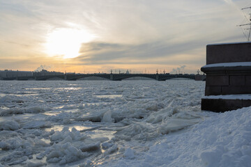 Ice on frozen Neva river, bridge, silhouettes of St. Petersburg buildings. St. Petersburg, the...