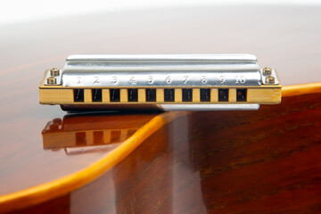 The harmonica rests on the body of a classical guitar. Classical musical wind instrument.