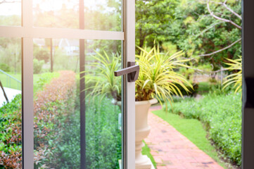 aluminium window with latch handle open with garden on background.