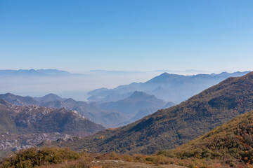 Panoramic view of dramatic karst mountain chains Dinaric Alps surrounding the Lake Skadar National Park seen from Goli Vrh, Montenegro, Balkan, Europe. Valley is covered by mystical fog, blue hills