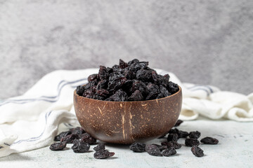 Fototapeta na wymiar Dried black grapes on stone background. Dried grapes in coconut bowl. Nuts varieties. Healthy eating. close up