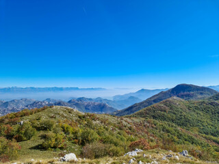 Fototapeta na wymiar Panoramic view of dramatic karst mountain chains Dinaric Alps surrounding the Lake Skadar National Park seen from Goli Vrh, Montenegro, Balkan, Europe. Valley is covered by mystical fog, blue hills