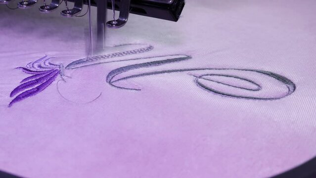 Embroidery design, alphabet M monogram and butterfly. Video of machine Embroidery on a cotton towel with grey thread. Selective focus Close up.