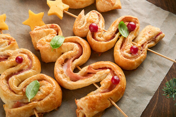 Christmas or New Year appetizer. Christmas tree shape puff pastry buns with cheese and ham. Group of Christmas tree shapes on wooden board. Festive idea for Christmas or New Year dinner. Top view.