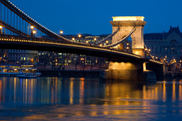 Obraz premium The Chain Bridge, Budapest, Hungary. Looking towards Pest, night time. Lighte reflected in the water of the Danube.