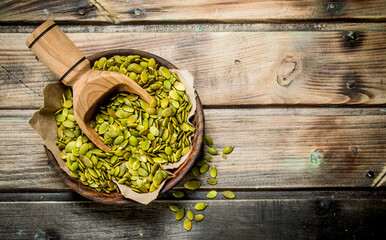 Pumpkin seeds in bowl with scoop.