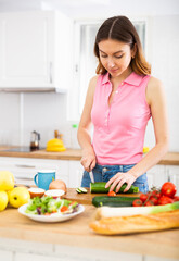 Obraz na płótnie Canvas Woman cutting vegetables cooking dinner at home