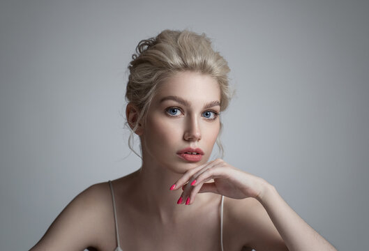Fashion portrait of blonde girl with twist hairstyle. Grey background.