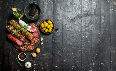 Variety of smoked salami with olives, herbs and spices.