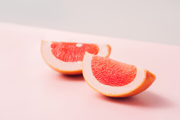 Two grapefruit slices against a green-pink background.