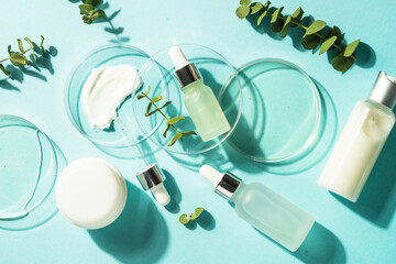 Cosmetic laboratory concept . Glass petri dish with cosmetic products and serum bottles at blue...