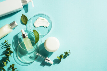 Cosmetic laboratory concept . Glass petri dish with cosmetic products and serum bottles at blue background. Flat lay image with copy space. - Powered by Adobe