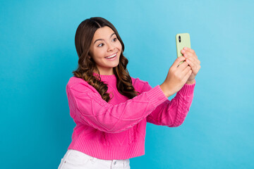 Photo of young funny schoolgirl teenager cute kid wear pink pullover hold smartphone take shot online video call isolated on blue color background