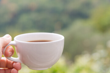Cup of coffee in the hand on the terrace