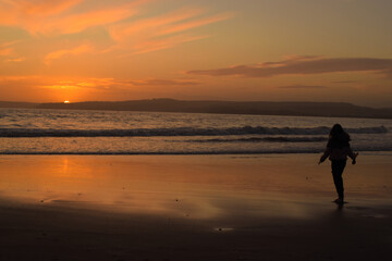 Fototapeta na wymiar Silhouette of a person walking on the beach