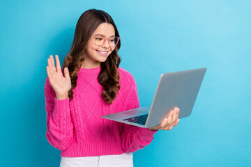 Photo of young schoolgirl teen aged lady wear pink knitted jumper raise palm hello friends online video call laptop isolated on blue color background