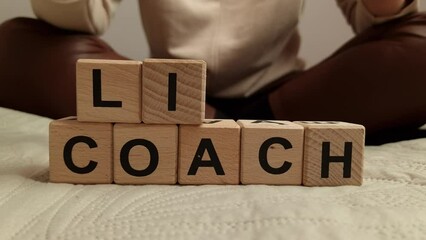 Woman composes the text life coach from wooden blocks. Mentoring, inspiration, motivation concepts