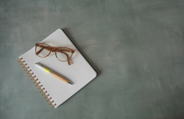 Cahier ouvert sur une page blanche avec stylo et lunettes