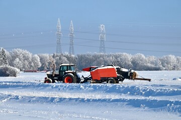 a farm tractor and baler covered with snow
