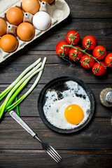Fried egg in a pan with a cassette of fresh eggs.