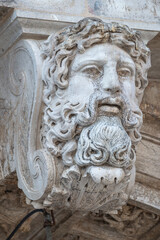 Portrait of ancient aged sculpture of old Venetian bearded man in Venice, Italy, closeup, details