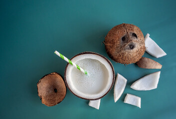 Coconut and pieces of broken coco nut on the blue teal background. Opened and whole cocoses with...