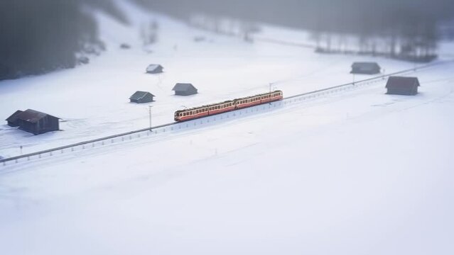 Cinematic drone aerial view of red train going through the mountains in winter