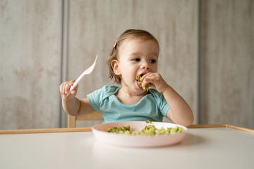 one girl small caucasian child one year old eat at the table at home