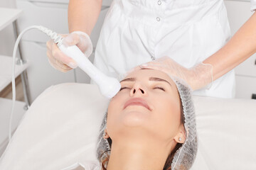Cosmetologist makes RF lifting for rejuvenation woman face, anti aging cosmetic procedure in beauty...