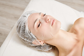 Young woman in sheet mask on face for rehydrate face skin, anti wrinkles cosmetic procedure in...