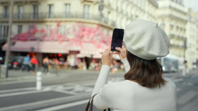 Young woman taking photo of French street bistro
