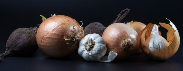 Vegetables on a black background. Onions, garlic and beets next to each other. Soup set