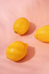 Lemons on soft pastel pink background, with shadows, summer and citrus aesthetic