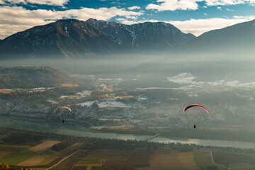 two paraglider in front of river Drau and the hochobir mountain in the backdrop.