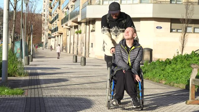 Disabled person walking having fun with friend in wheelchair on the street
