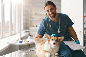 Happy young professional veterinary doctor with purebred corgi dog
