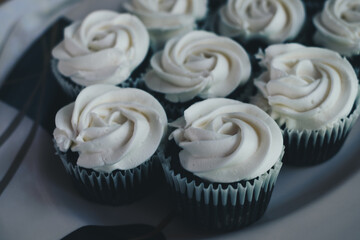 Bunch of delicious chocolate cupcakes with vanilla white cream topping on white serving plate. Selective focus.

