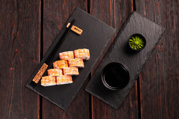 Japanese kitchen - sushi roll with cucumber and cream cheese topped with shrimp on black board top view