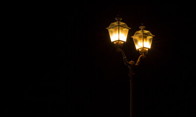 Closeup of a street lamp at night. The light inside brightens the atmosphere.