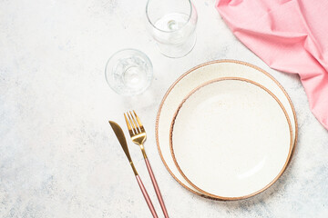 Table setting with plate, flowers and cutlery at white kitchen table. Spring or summer table...