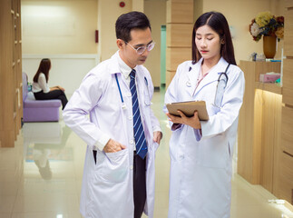Two professional doctors using a digital tablet discuss patient diagnosis in the hospital..