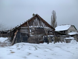 Wooden skewed house in the field. The wooden building fell into disrepair. Old, ruined house from a...