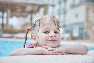child girl 4 years old swims in the pool in the summer outdoors