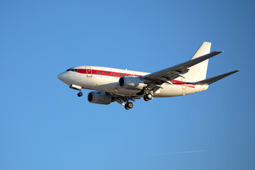 Avion de ligne volant en phase de de montée, trains d'atterrissage encore sortis. Avion à réacteurs blanc et rouge sur fond de ciel bleu.