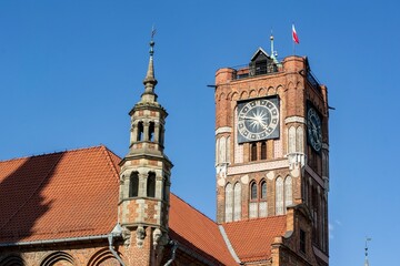 Torun town hall of Ratusz Staromiejski clock tower from 18th century with Polish flag