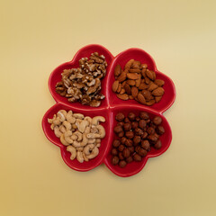 4 types of nuts in a plate in the form of hearts, Greece nuts, almonds, cashews and hazelnuts in a plate divided into 4 parts in the form of hearts