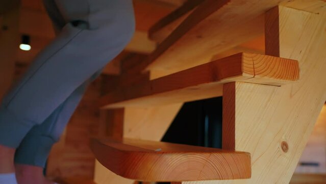 A person in gray tracksuit and white socks walks up the wooden stairs. Close up shot. High quality 4k footage