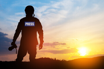 Photojournalist silhouette documenting war or conflict. Photojournalist at sunset. War, army,...