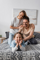 Fototapeta premium cheerful woman hugging happy husband tickling smiling daughter at home.