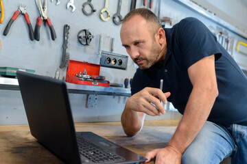 man looking computer in workshop